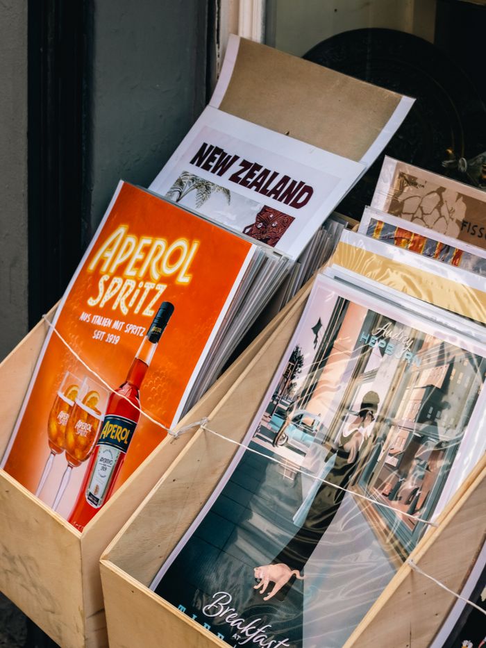 services-01 Assorted vintage posters in a wooden stand featuring travel and beverage themes.