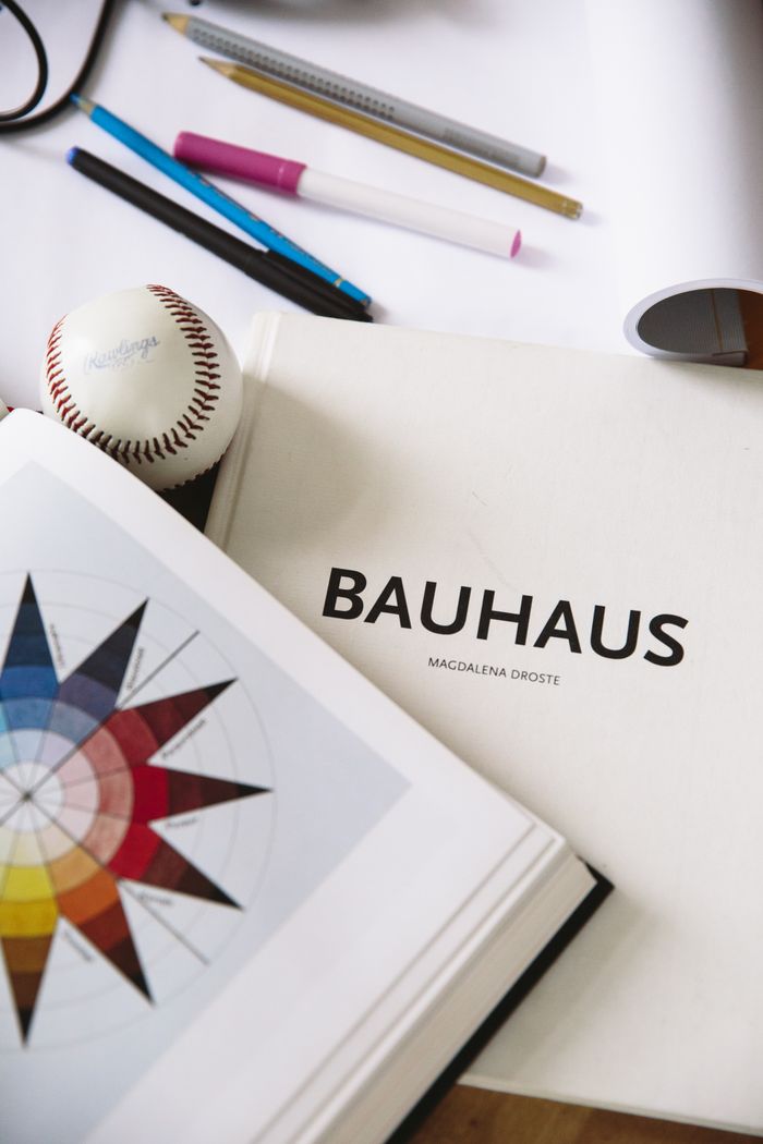 gallery-6 An artistic workspace featuring a Bauhaus design book, art supplies, and a baseball for inspiration.